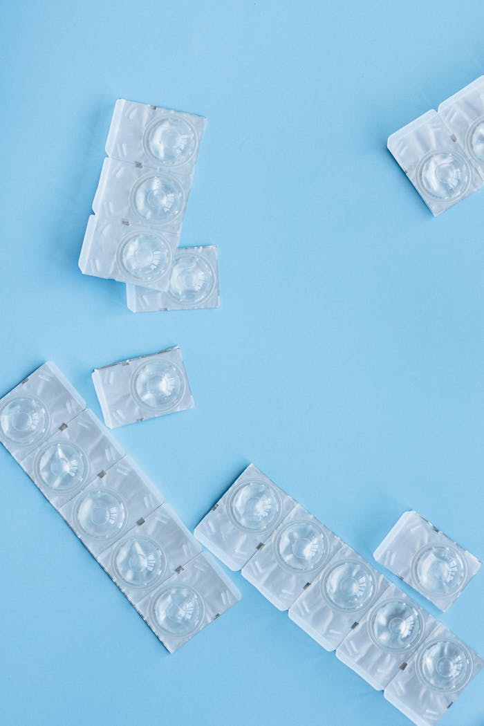 Clear contact lenses in blister packs arranged on a blue background.